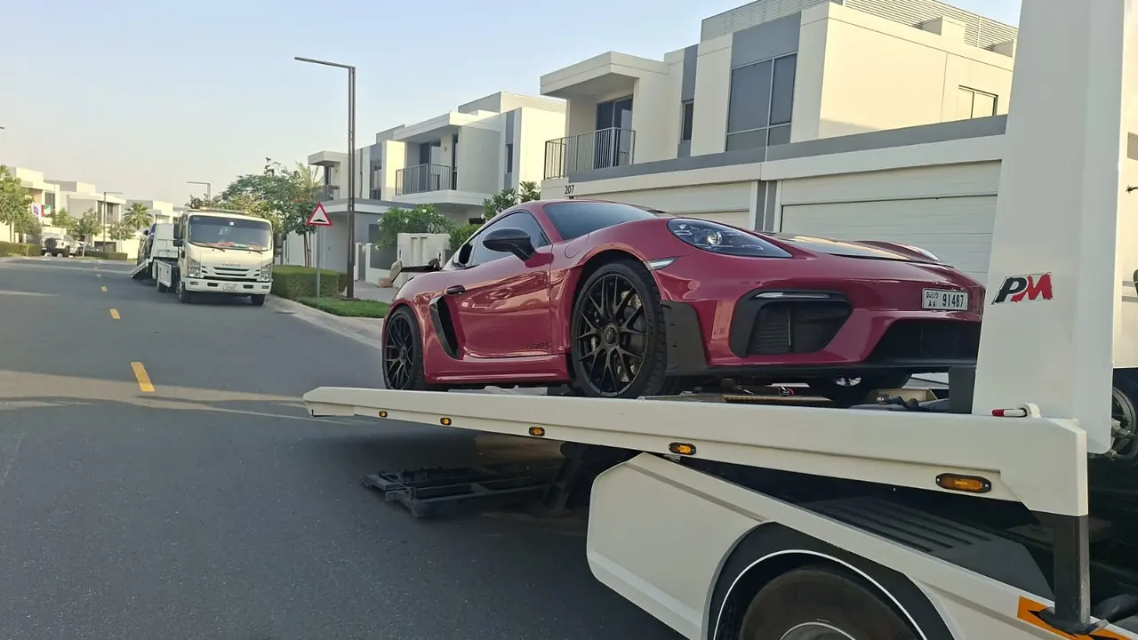 A sports car secured on a tow truck on a residential road